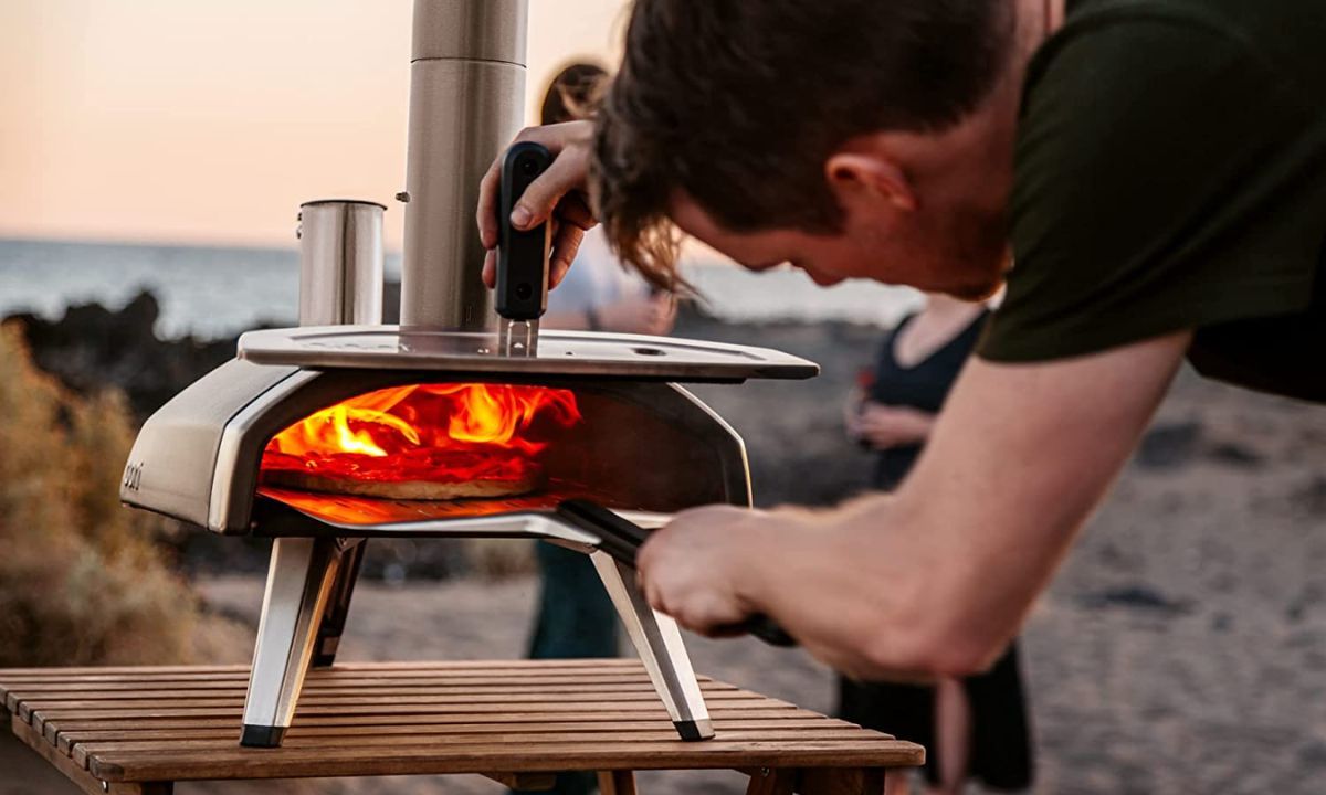 Gentleman carefully sliding the pizza off the pizza peel in the Ooni Fyra 12 oven
