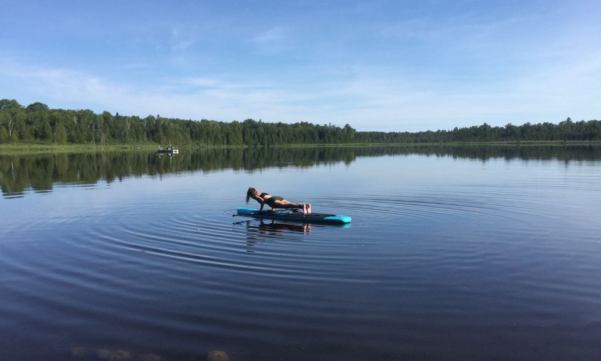 Woman making YOGA POSE on small lake on her Inflatable SUP