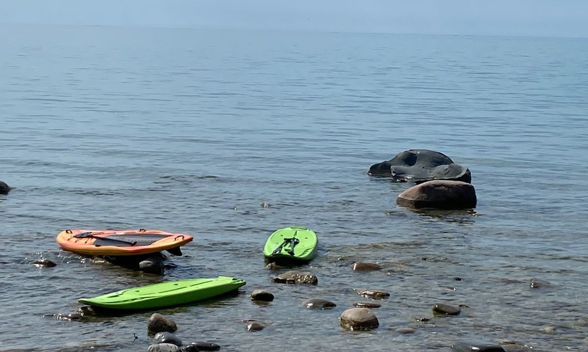 one adult and two kids paddle boards at Lake Huron