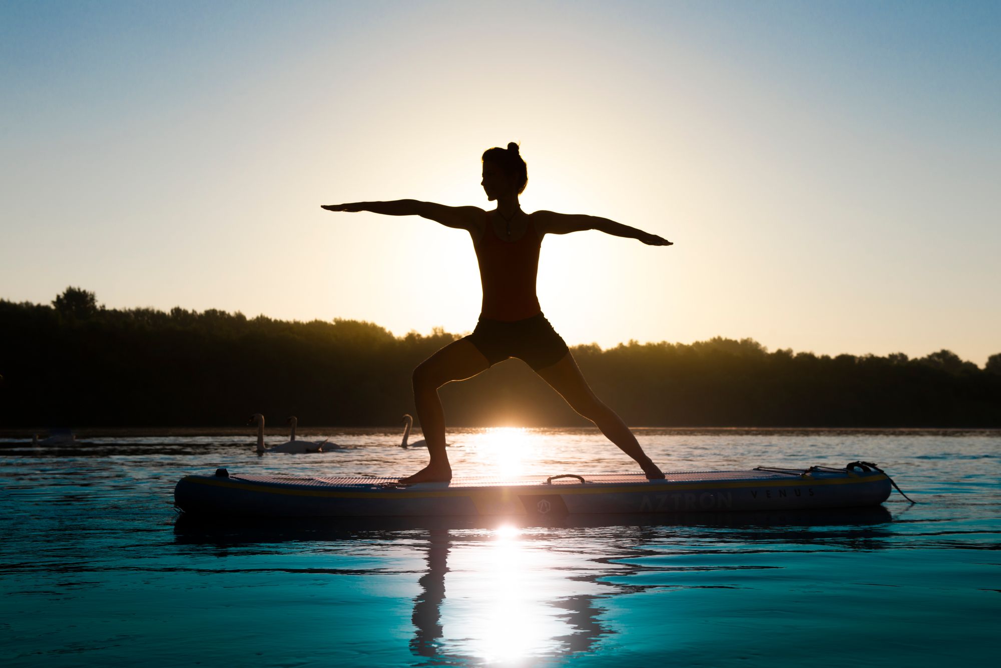 Woman in the warrior pose doing Yoga on her Paddle Board