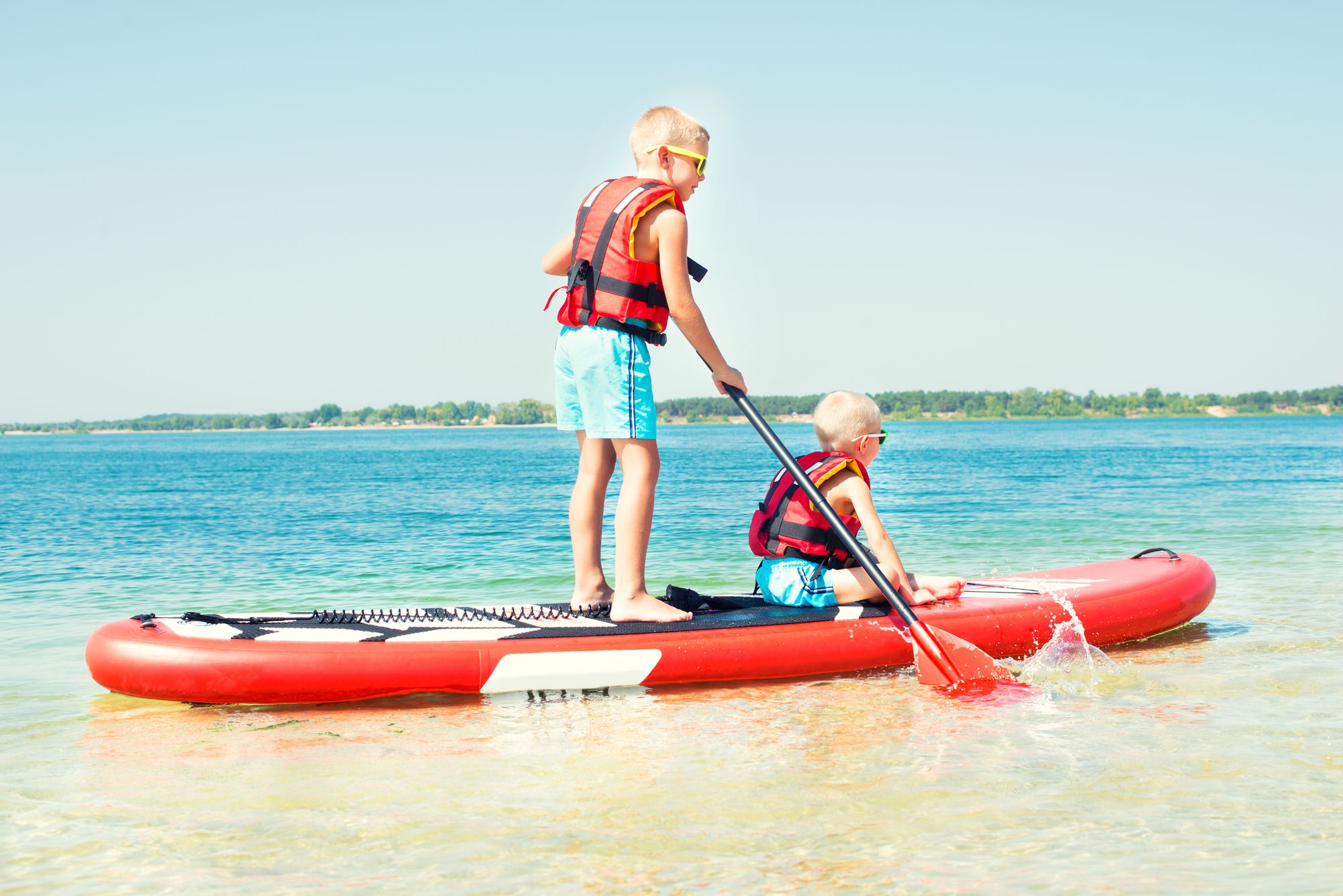 two children learning to paddle on a SUP Board with Safety PFD