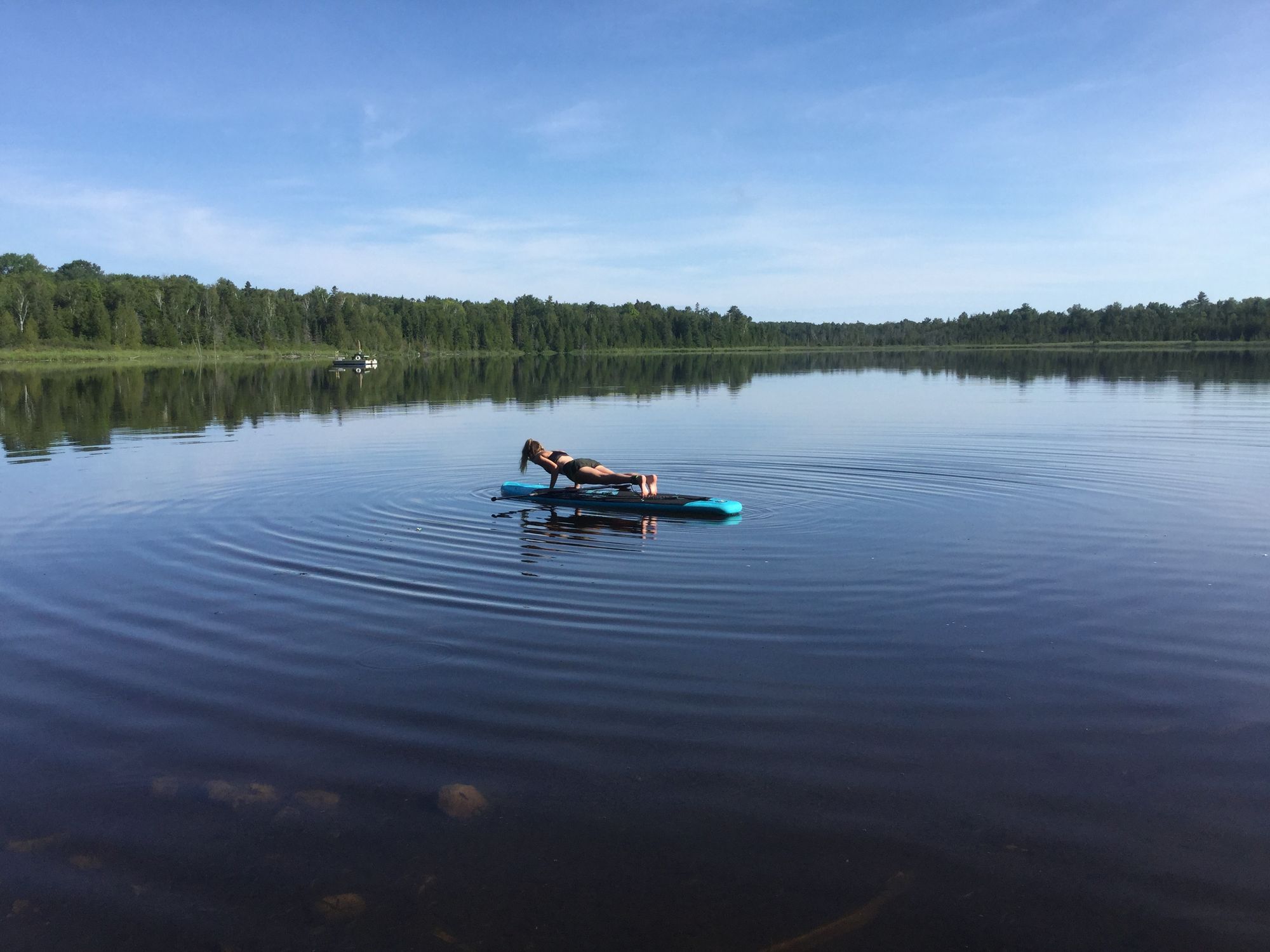 Plank Yoga Pose on Inflatable Paddle Board on calm lake