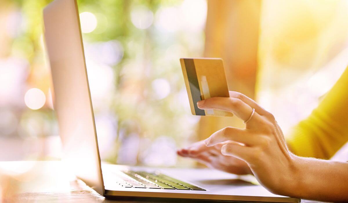 woman at her laptop with credit card in hand ready to finish her shopping