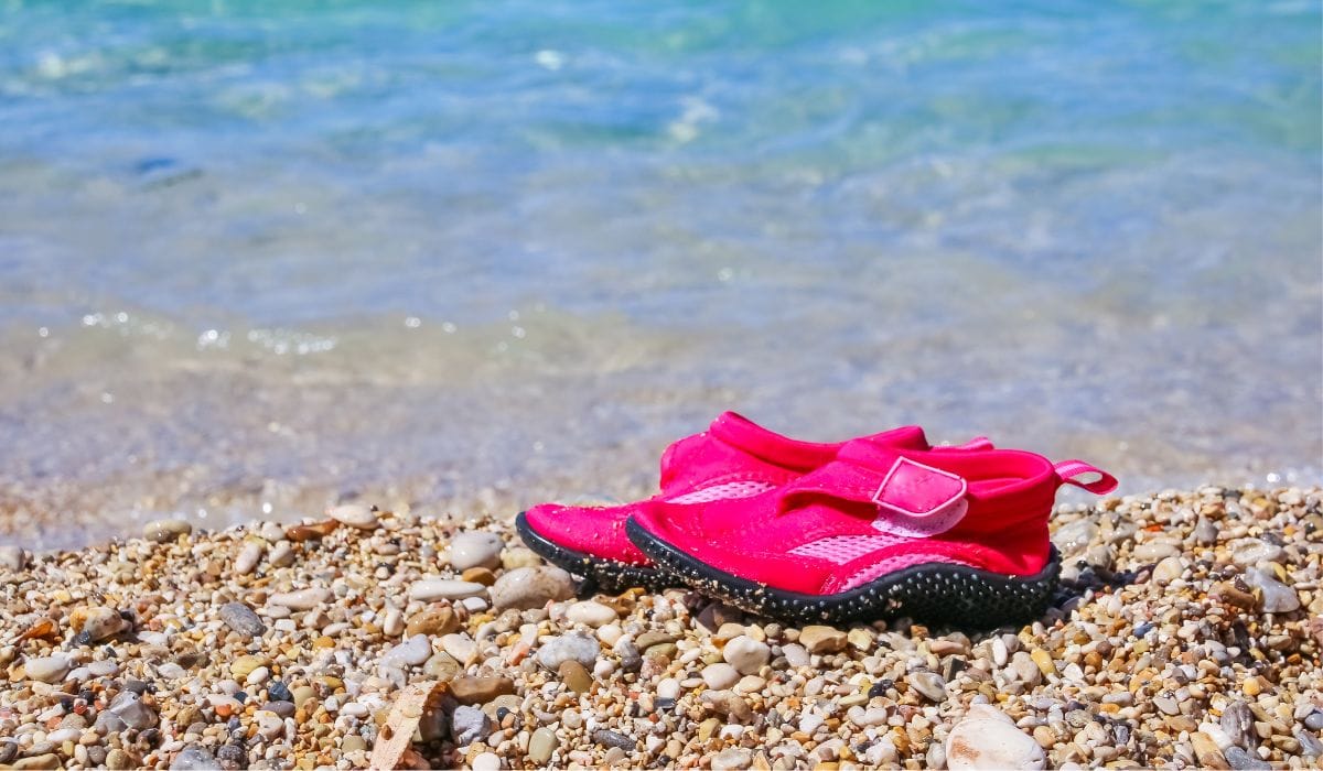 pink water shoes for toddler on shoe beside the lake