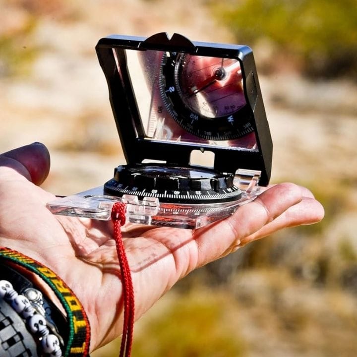 Transferring the bearing to the field - Hold the compass level in front of you with the direction of travel arrow pointing straight ahead