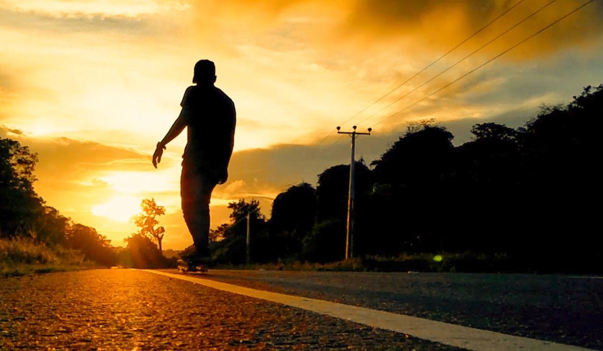 Skateboarding at sunset down highway with no easy way to stop.