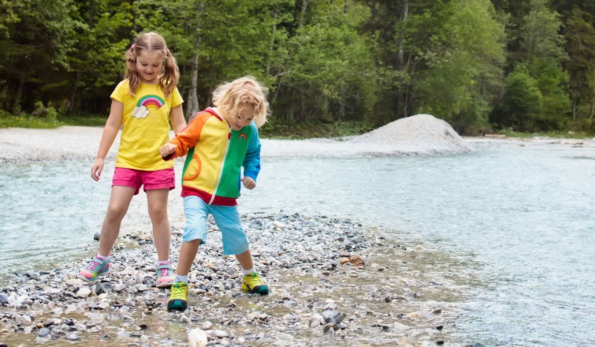 Young Girls at playing safely by the lake wearing water shoes