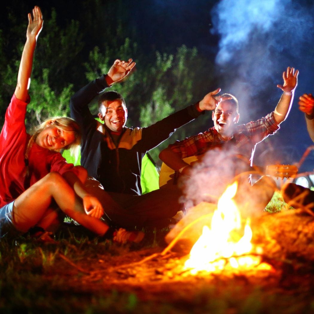 Friends around a fire playing campfire games.