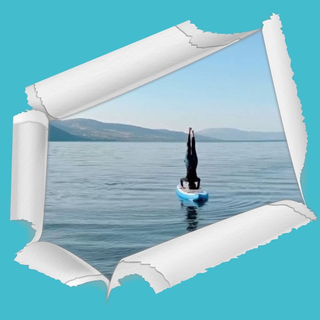 Person standing on head on a paddle board in the lake, YOGA SUP