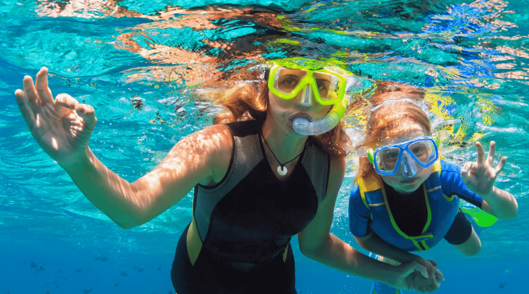Mother and daughter enjoy their swim goggles with nose cover for looking around under water.