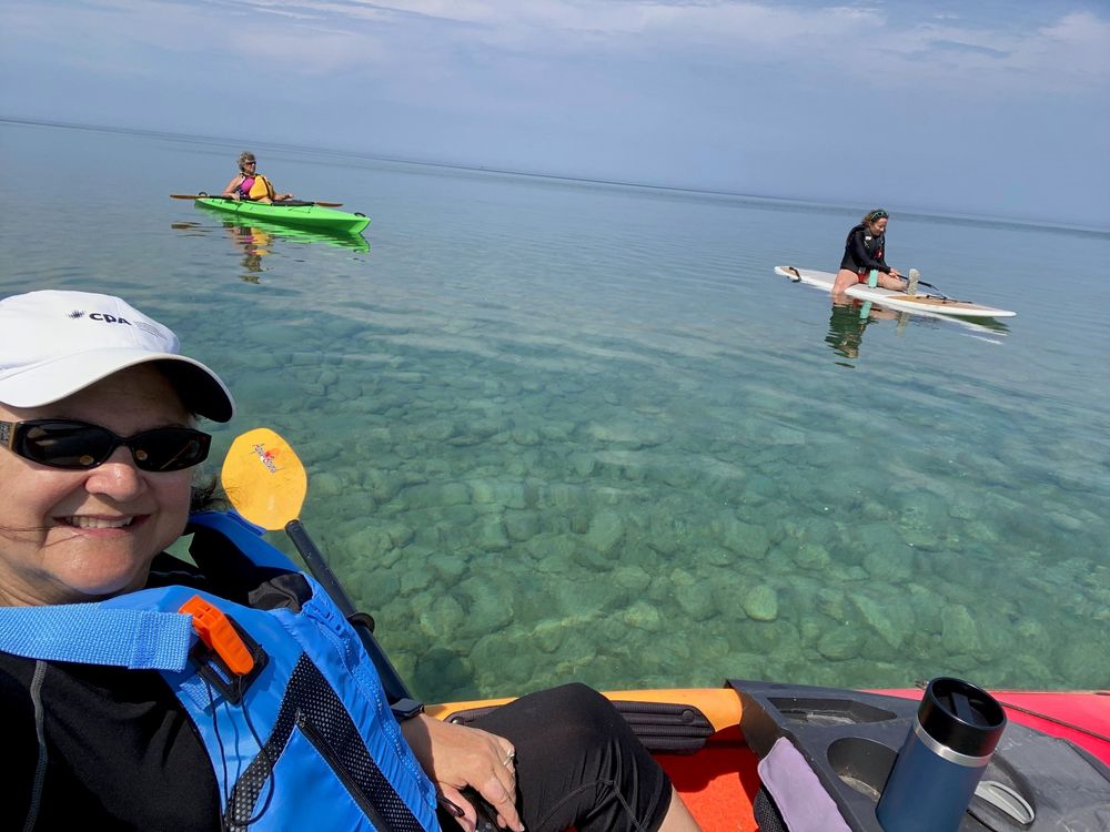 Three friends paddling, two in kayaks, one on paddle board. Is Kayak or Paddle Board Harder?